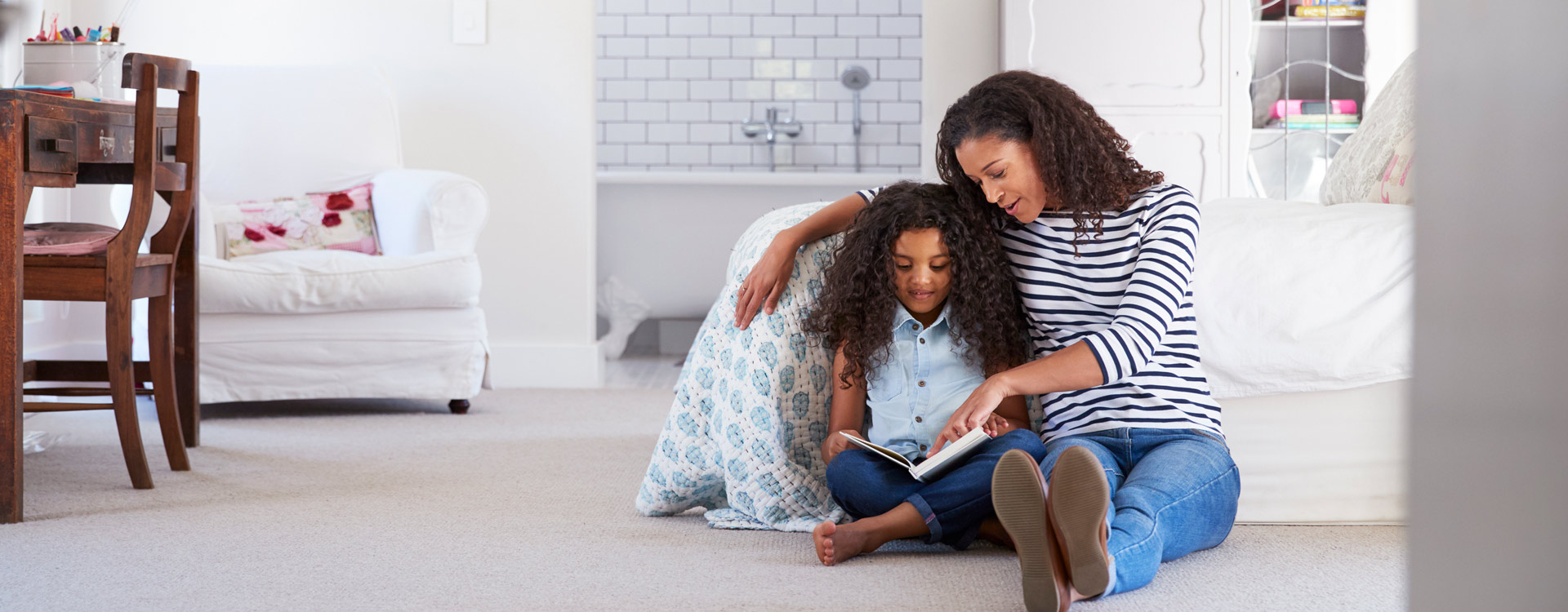 Mother reading with daughter in comfortable home